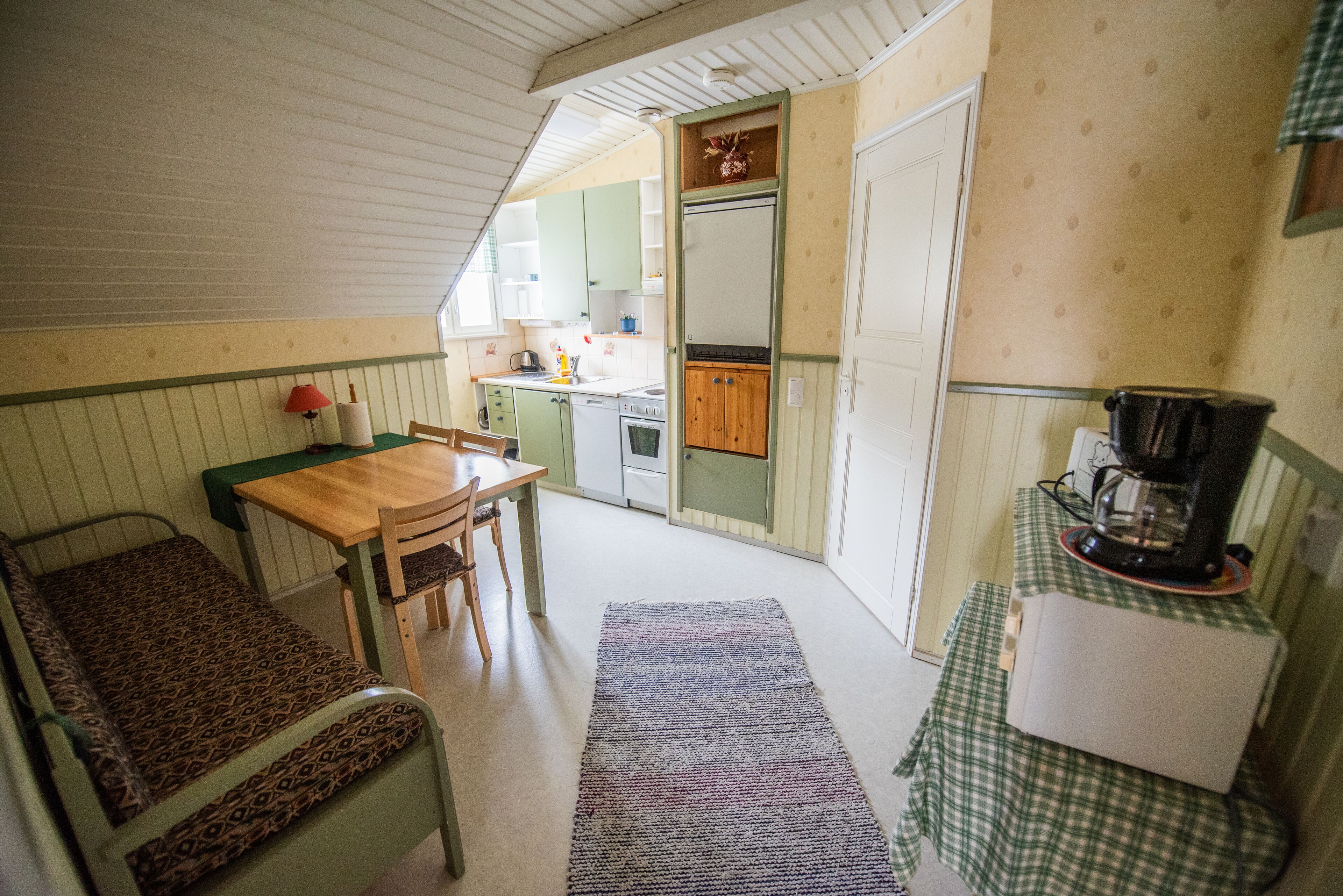 Una cocina compacta con comedor, un refrigerador pequeño y una cafetera.