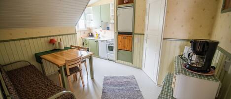 Una cocina compacta con comedor, un refrigerador pequeño y una cafetera.