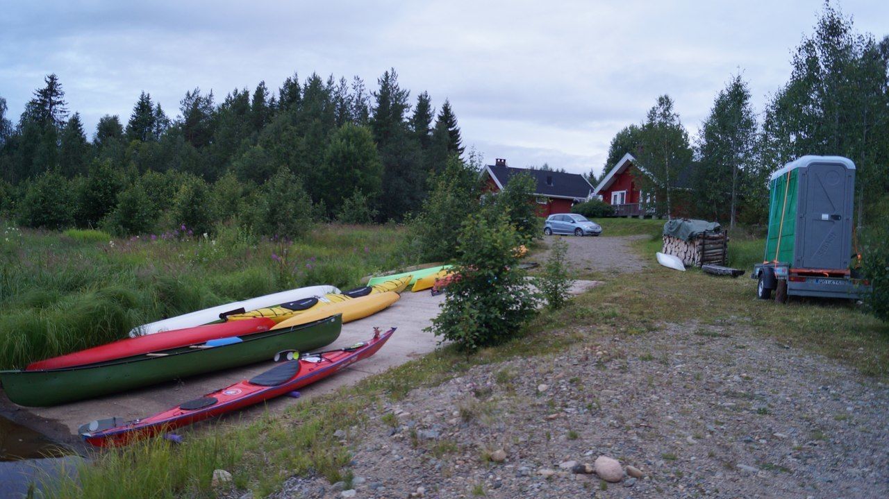 A gravel path leading to a house with kayaks lined up on the side.
