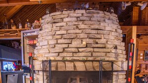 A stone fireplace with a metal screen, surrounded by stone walls and wooden beams. - Holiday Village Kuukiuru (Kemijarvi)
