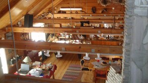 A multi-level wooden interior with exposed beams, a stone wall, and various items on shelves and tables. - Holiday Village Kuukiuru (Kemijarvi)