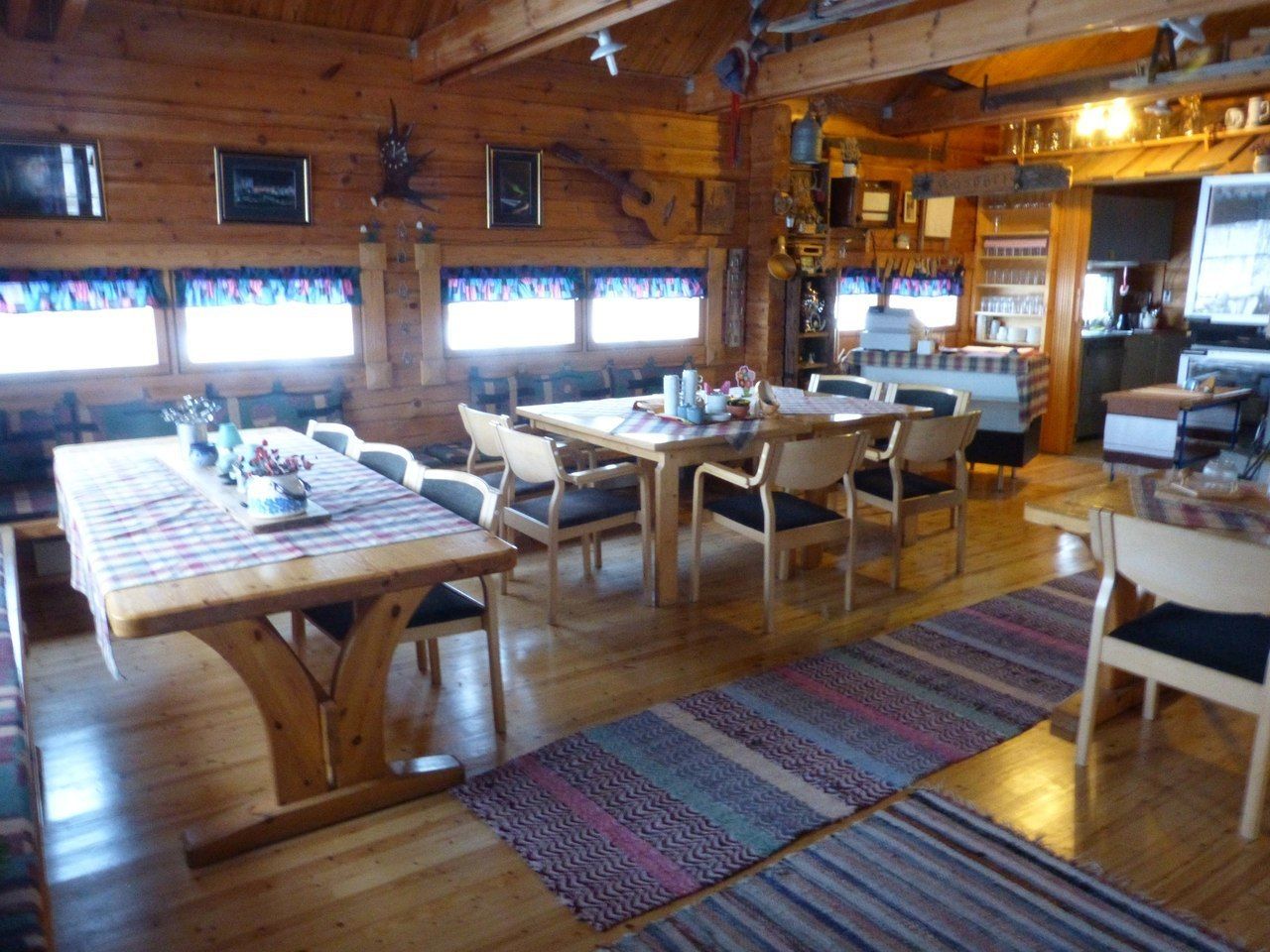 A wooden cabin interior with a dining area, kitchen, and bar.