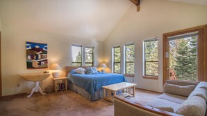 A bedroom with a bed, bedside tables, a chair, and a painting on the wall.