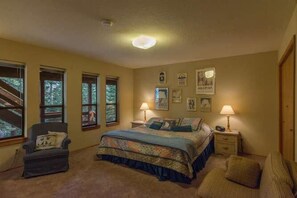 A bedroom with a large bed, two bedside tables, a chair, and a window with a view of trees. - Atkin 4 Bedroom Holiday Home By Tahoe Truckee (Truckee)