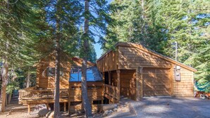 A wooden cabin with a deck, a garage, and a covered porch area surrounded by trees. - Gamara 3 Bedroom Holiday Home By Tahoe Truckee (Truckee)