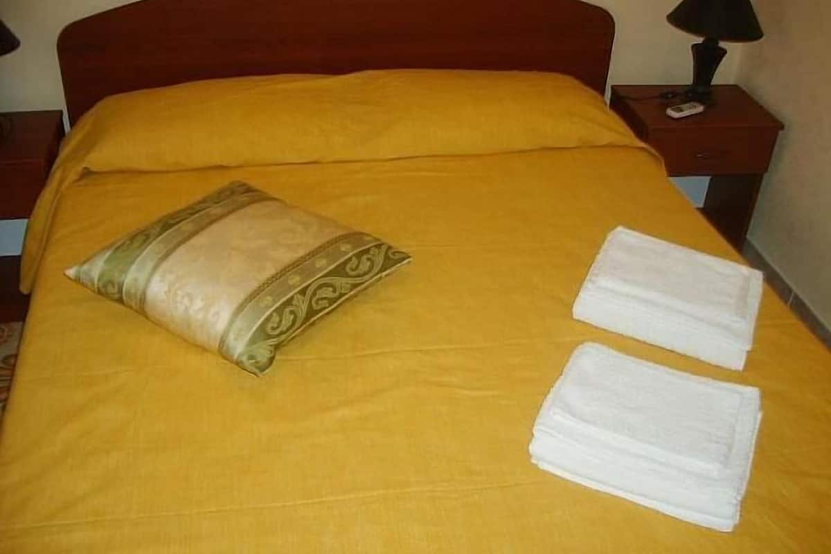 Un lit avec une couvre-lit jaune, un coussin décoratif et deux serviettes pliées.