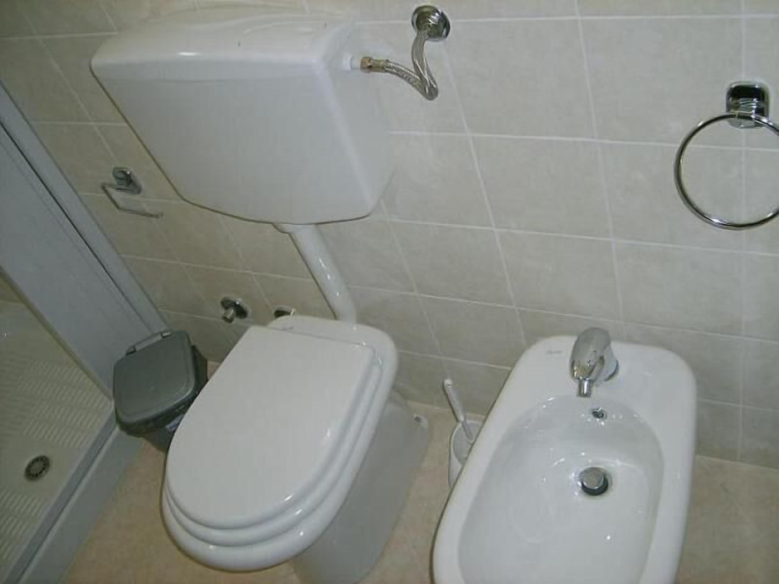 A bathroom with a toilet, bidet, and a sink.