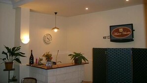 A reception area with a clock, a framed sign, and potted plants.