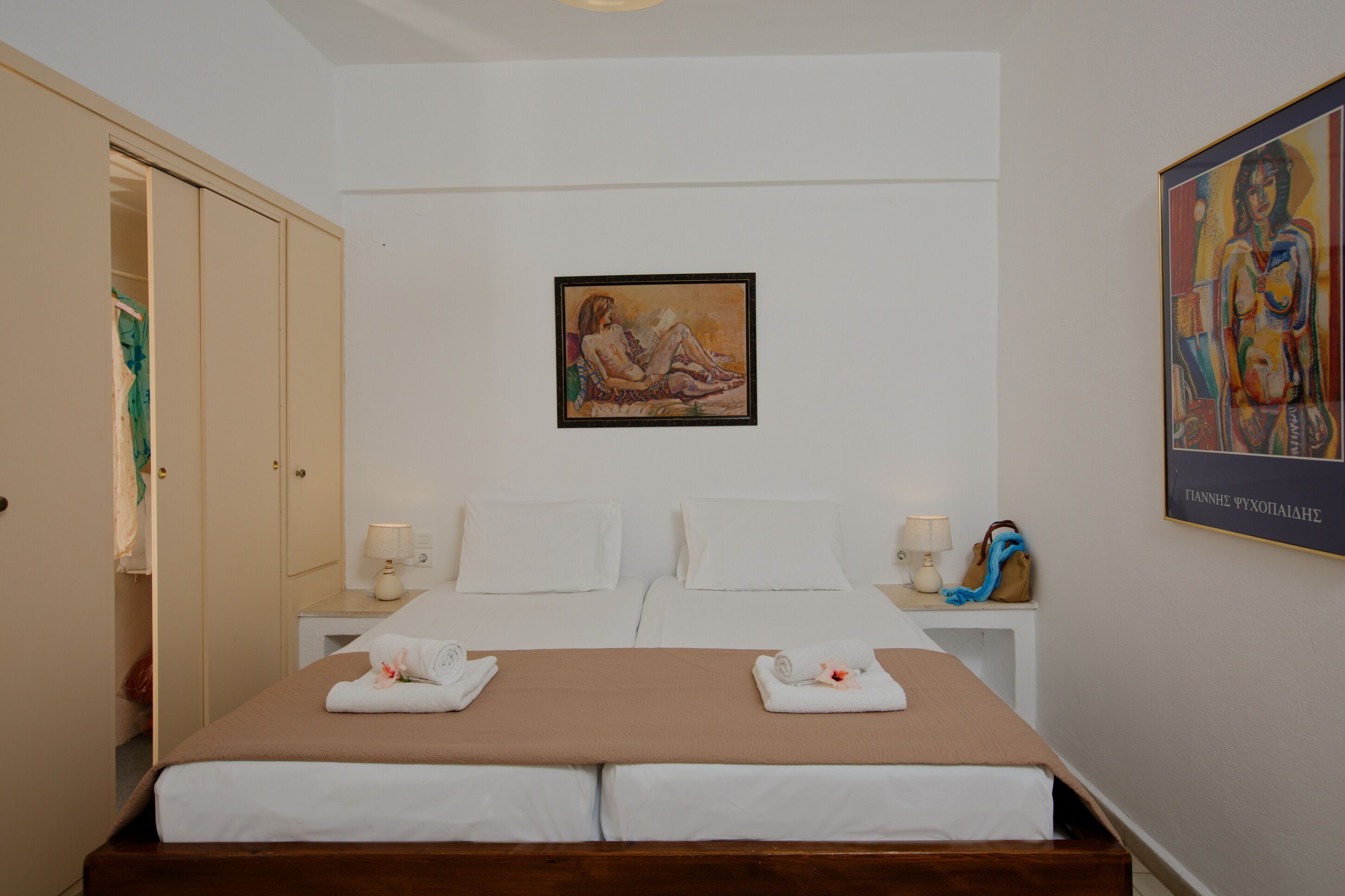 Una camera d'albergo con un letto, due comodini, un armadio e un quadro appeso al muro.
