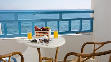 Un balcón con una mesa dispuesta con frutas, vasos de zumo de naranja y gafas de sol.
