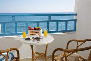 A balcony with a table set with fruits, glasses of orange juice, and sunglasses. - Elalia Apartments (Hersonissos)