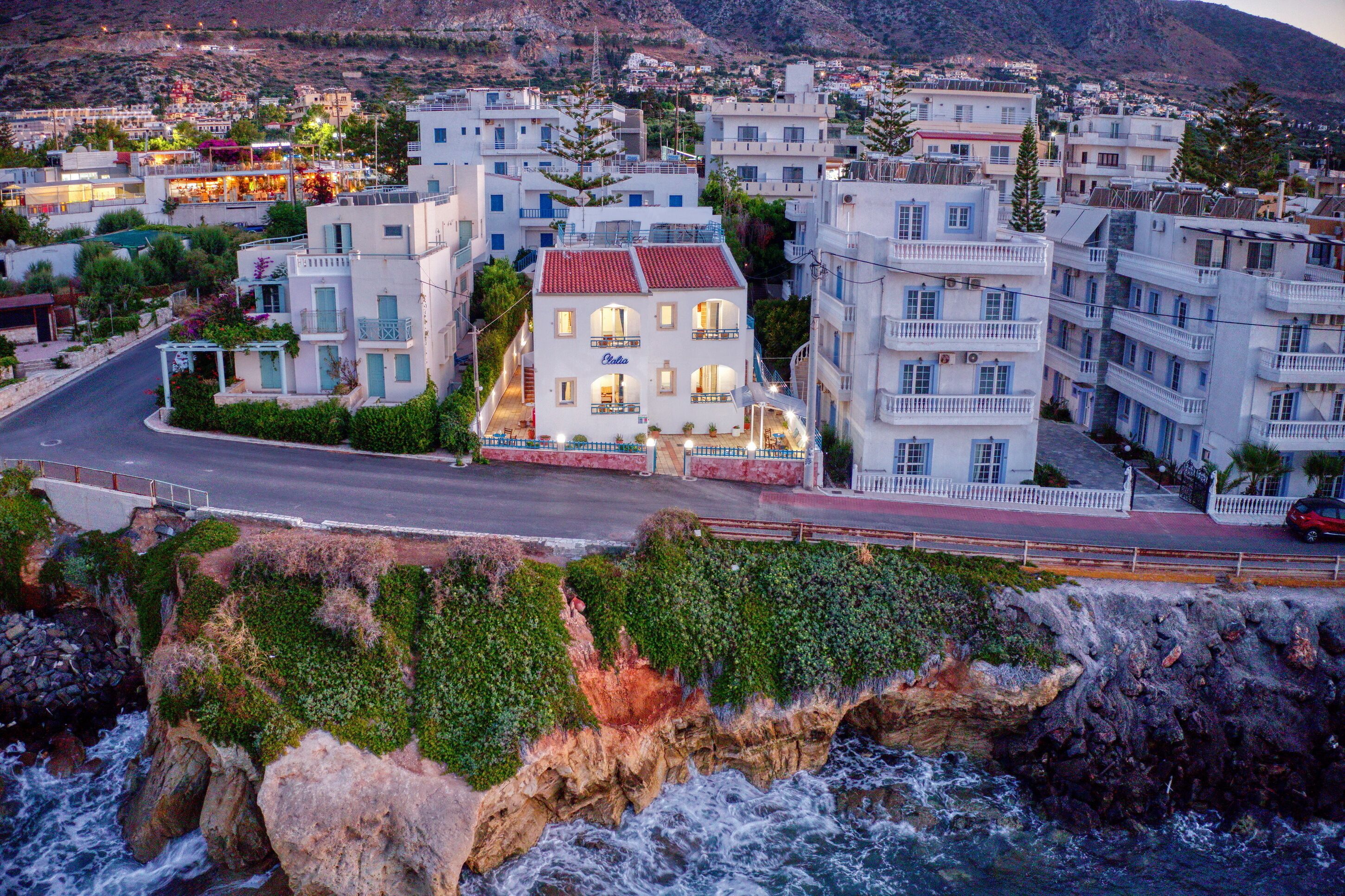 Un pueblo costero con edificios a lo largo de la costa, que presenta balcones y un edificio destacado con tejado rojo.