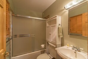Un baño con ducha, inodoro, lavabo y una toalla colgada en la pared.