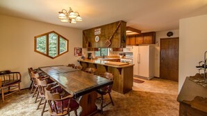A rustic kitchen with a large wooden table and chairs, a built-in island, wooden cabinets, and a clock on the wall. - Kelly 3 Bedroom Holiday Home By Tahoe Truckee (Truckee)