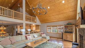 A spacious living room with a high ceiling, wooden beams, a large sofa set, a coffee table, and a fireplace. - Falcon Point 3 Bedroom Holiday Home By Tahoe Truckee (Truckee)
