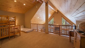 A cozy attic bedroom with a sloped ceiling, a ceiling fan, a bunk bed, a desk with a globe, and a fireplace. - Falcon Point 3 Bedroom Holiday Home By Tahoe Truckee (Truckee)
