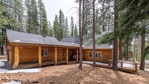 A log cabin with a porch, surrounded by tall pine trees. - Falcon Point 3 Bedroom Holiday Home By Tahoe Truckee (Truckee)