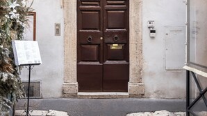 A building entrance with a dark brown door, a decorative archway, and a number '26' sign. - 59 Steps Trevi (Rome)
