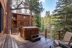 A wooden deck with a hot tub, seating, and a view of a forest. - Serventi 3 Bedroom Holiday Home By Tahoe Truckee (Truckee)