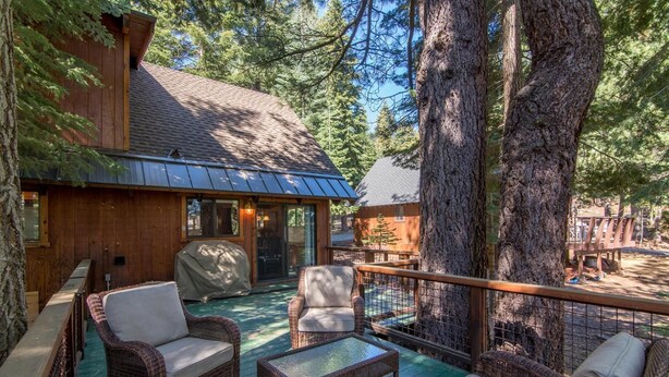 A wooden cabin with a covered patio, wicker furniture, and a view of surrounding trees. - Saunders 3 Bedroom Holiday Home By Tahoe Truckee (Truckee)