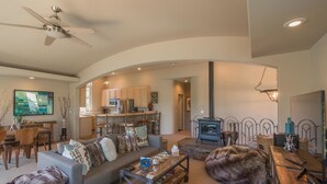 A spacious living area with a sofa, coffee table, and a large dog. There is a kitchen in the background, a fireplace, and a ceiling fan. - Palisades 4 Bedroom Holiday Home By Tahoe Truckee (Truckee)