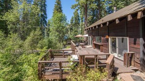 A wooden cabin with a deck, surrounded by dense forest. - South Shore 5 Bedroom Holiday Home By Tahoe Truckee (Truckee)