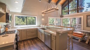 A modern kitchen with a central island, large windows, and a dining area with a bench. - South Shore 5 Bedroom Holiday Home By Tahoe Truckee (Truckee)