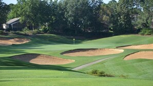 A golf course with bunkers, a flag, and a clear path.