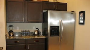 A kitchen with dark wooden cabinets, a stainless steel refrigerator, a toaster, and a kettle on the countertop. - Gorgeous Home with Golf Course View (Haines City)