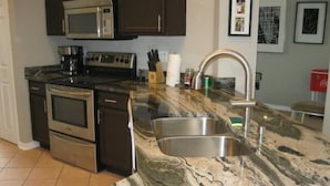 A kitchen with stainless steel appliances, a granite countertop, and a sink. - Gorgeous Home with Golf Course View (Haines City)