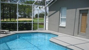 A swimming pool with a clear view of the surrounding landscape, including trees and a golf course. - Gorgeous Home with Golf Course View (Haines City)