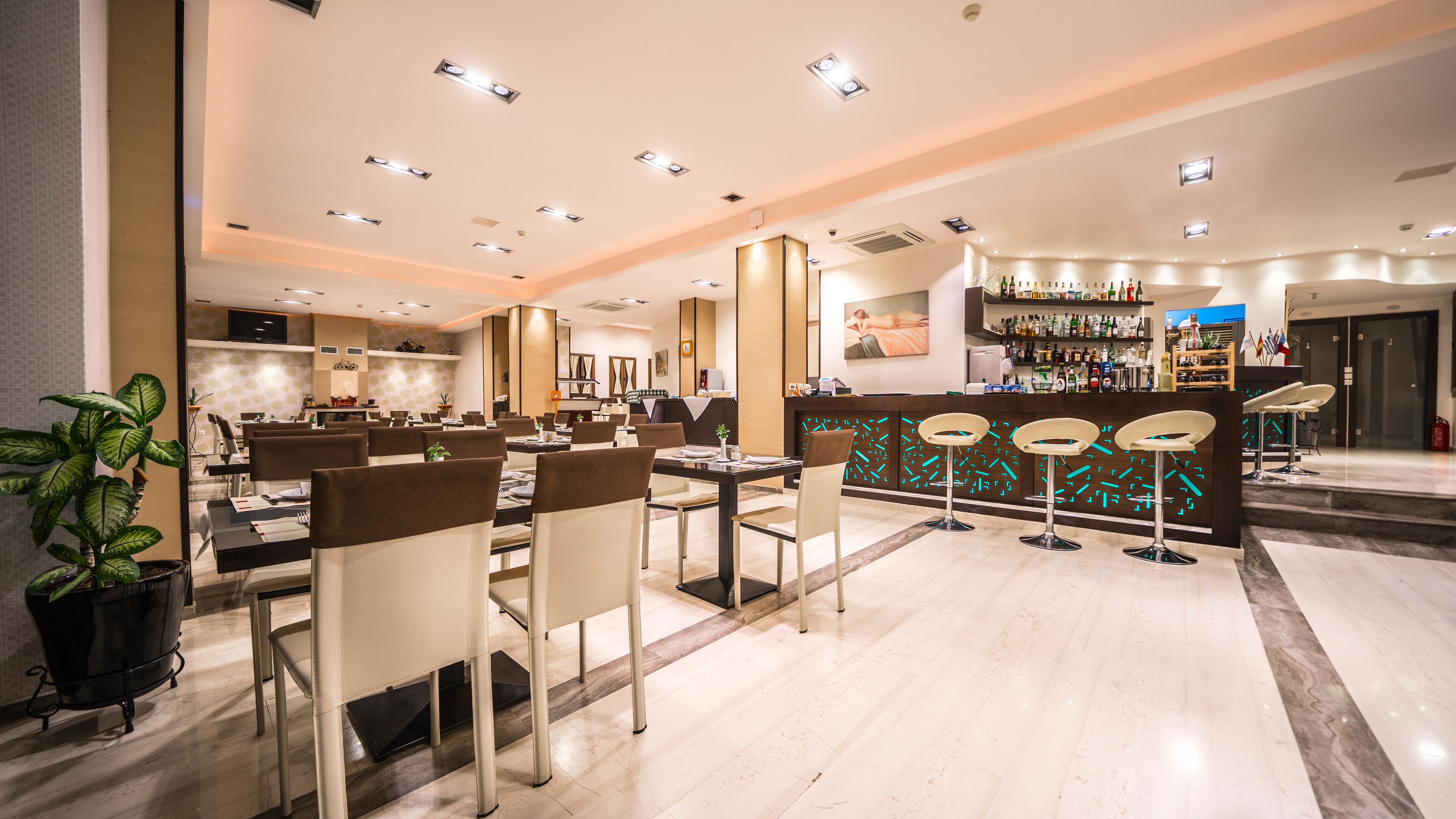 Um lobby moderno de hotel com área de bar, espaço para refeições e balcão de recepção.