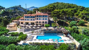 Un hotel con piscina, mobiliario exterior y vistas al paisaje circundante.