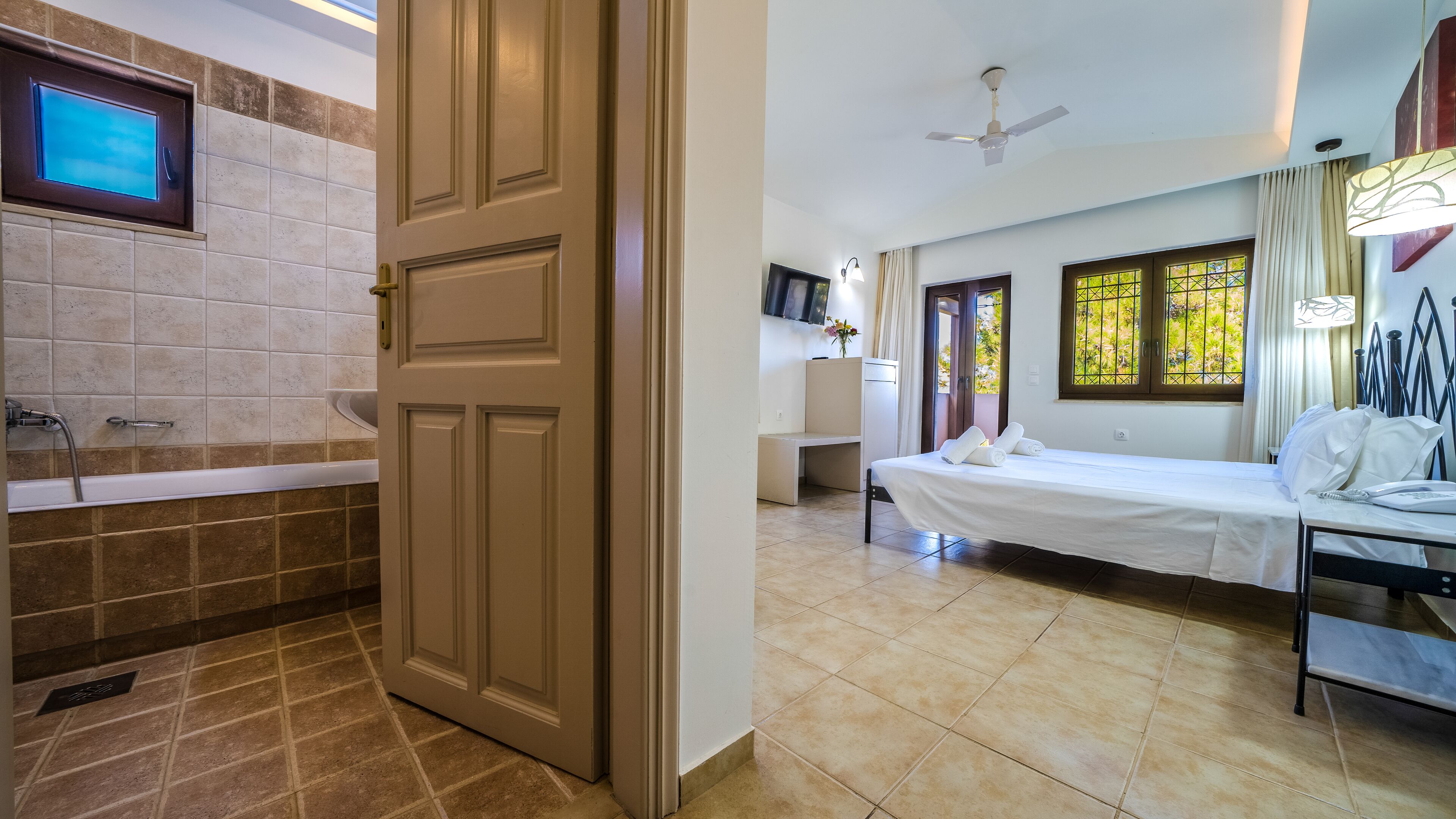 Una habitación de hotel con baño, cama, escritorio y televisión.