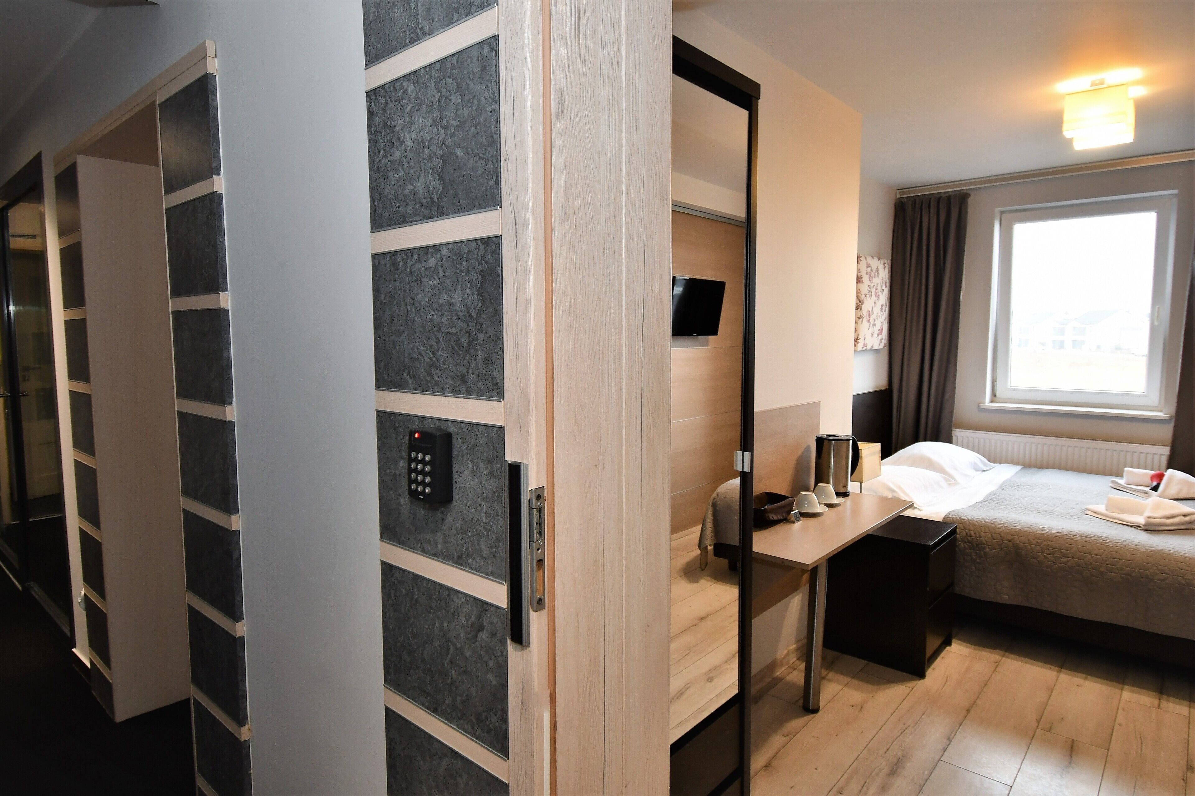Una habitación de hotel con cama, mesita de noche y armario con televisión integrada.