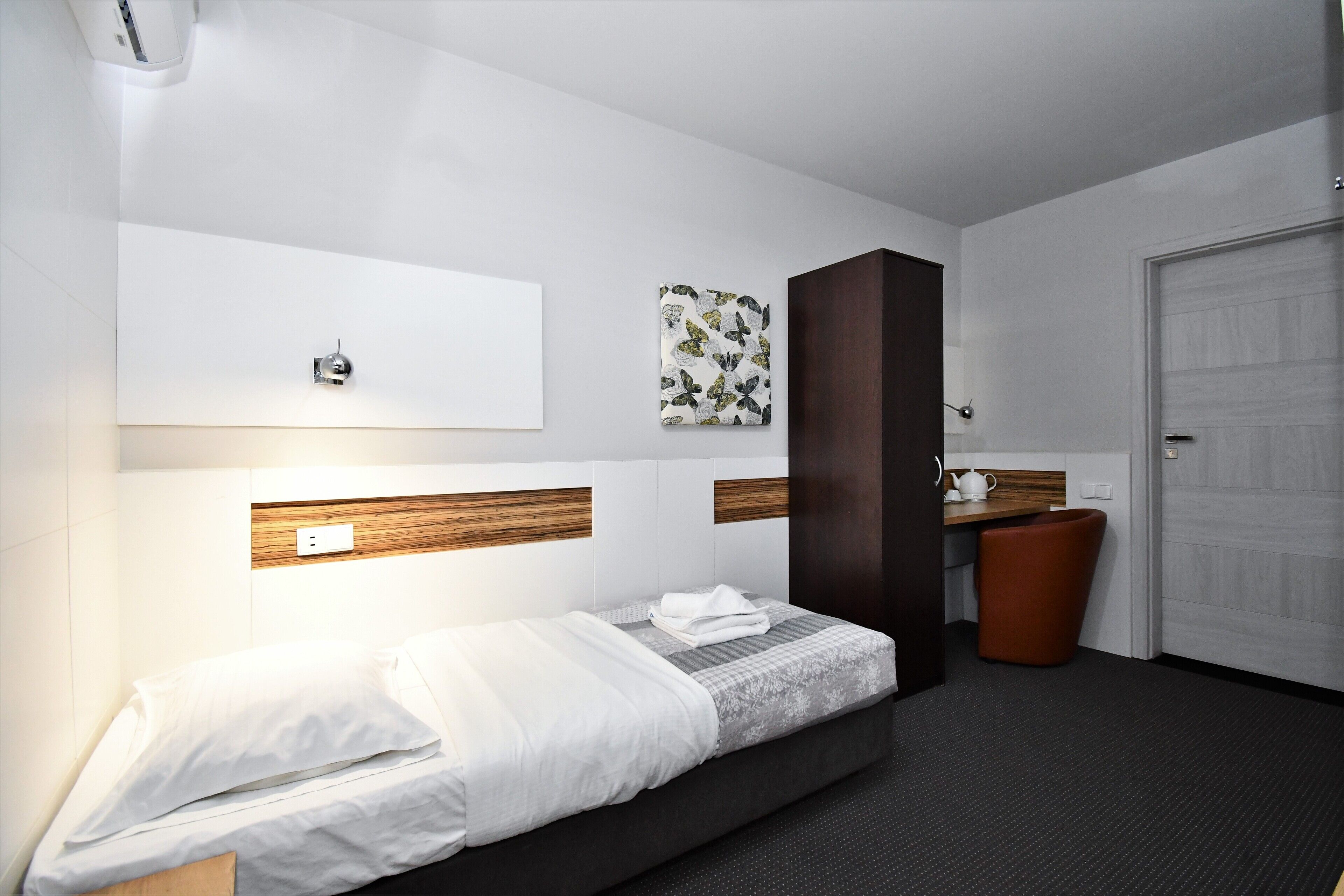 Una habitación de hotel moderna con una cama, un escritorio y una puerta.