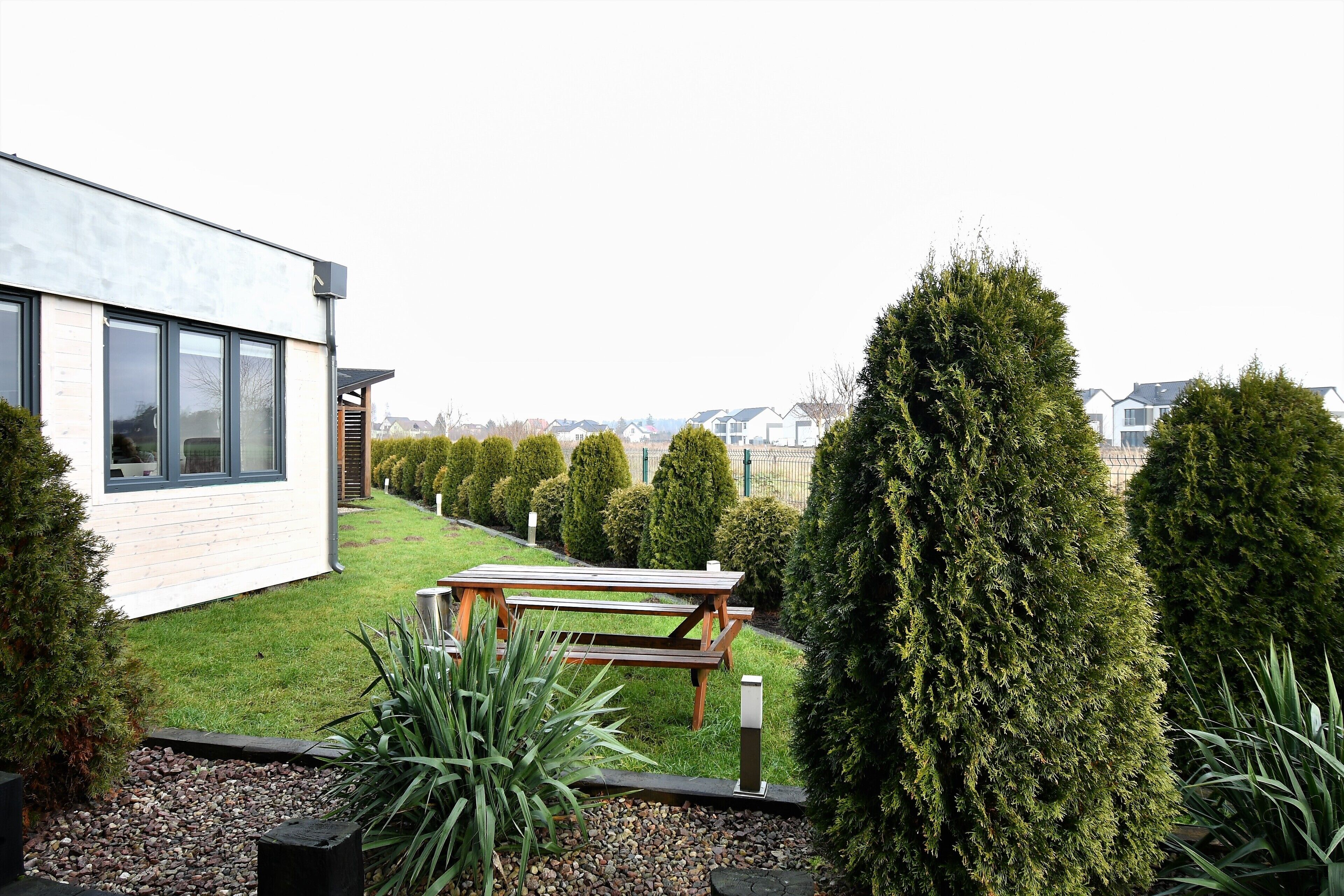 A modern house with a patio, neatly trimmed hedges, and a view of neighboring houses.