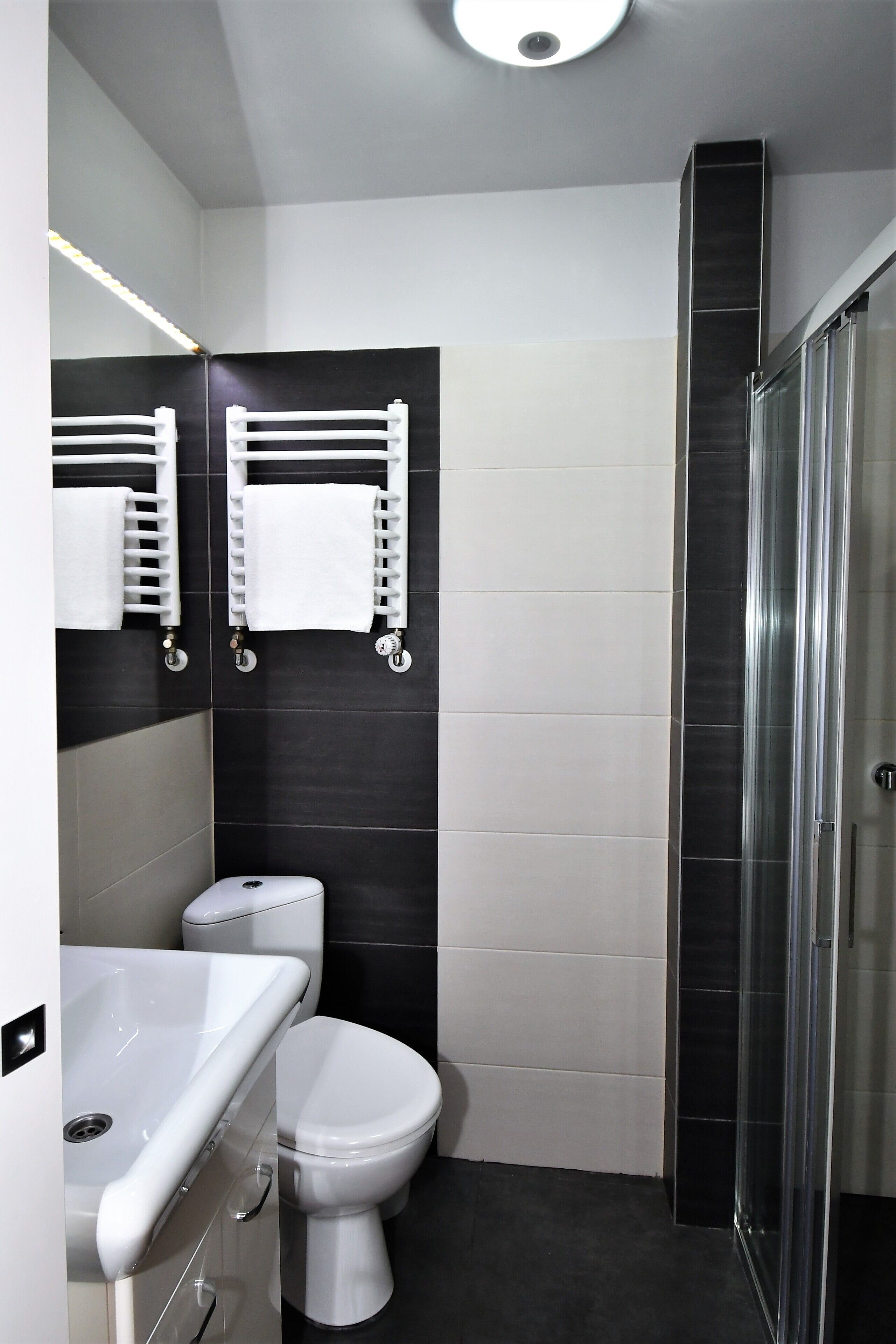 A modern bathroom with a white toilet, a sink, and a glass shower enclosure.