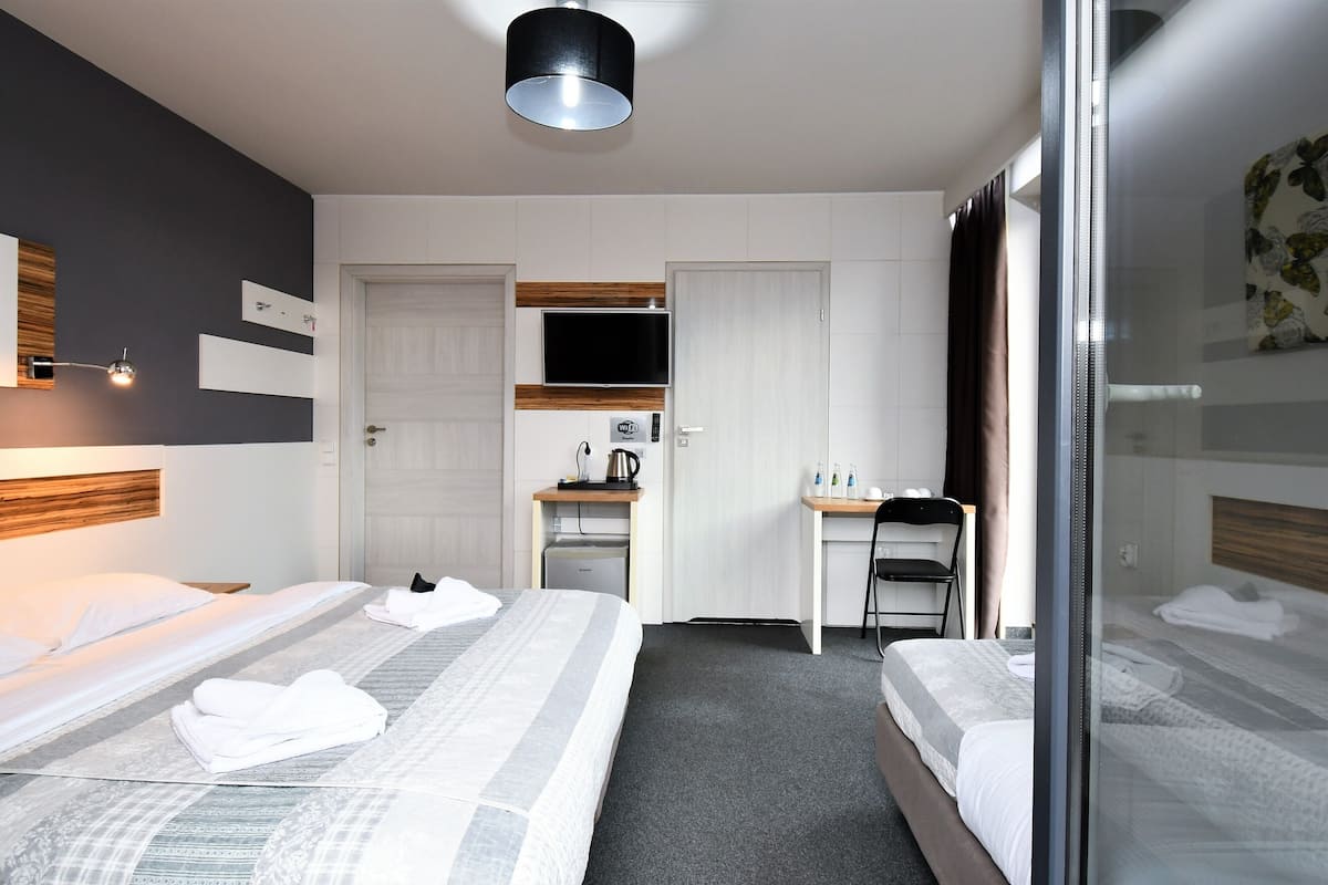 Habitación de hotel con dos camas, un escritorio, una silla, un televisor y un baño con ducha.