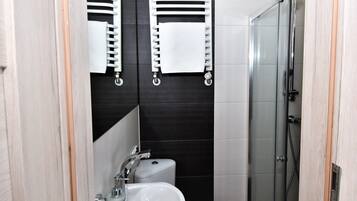 Une salle de bain avec un lavabo blanc, des toilettes et une douche à parois de verre.