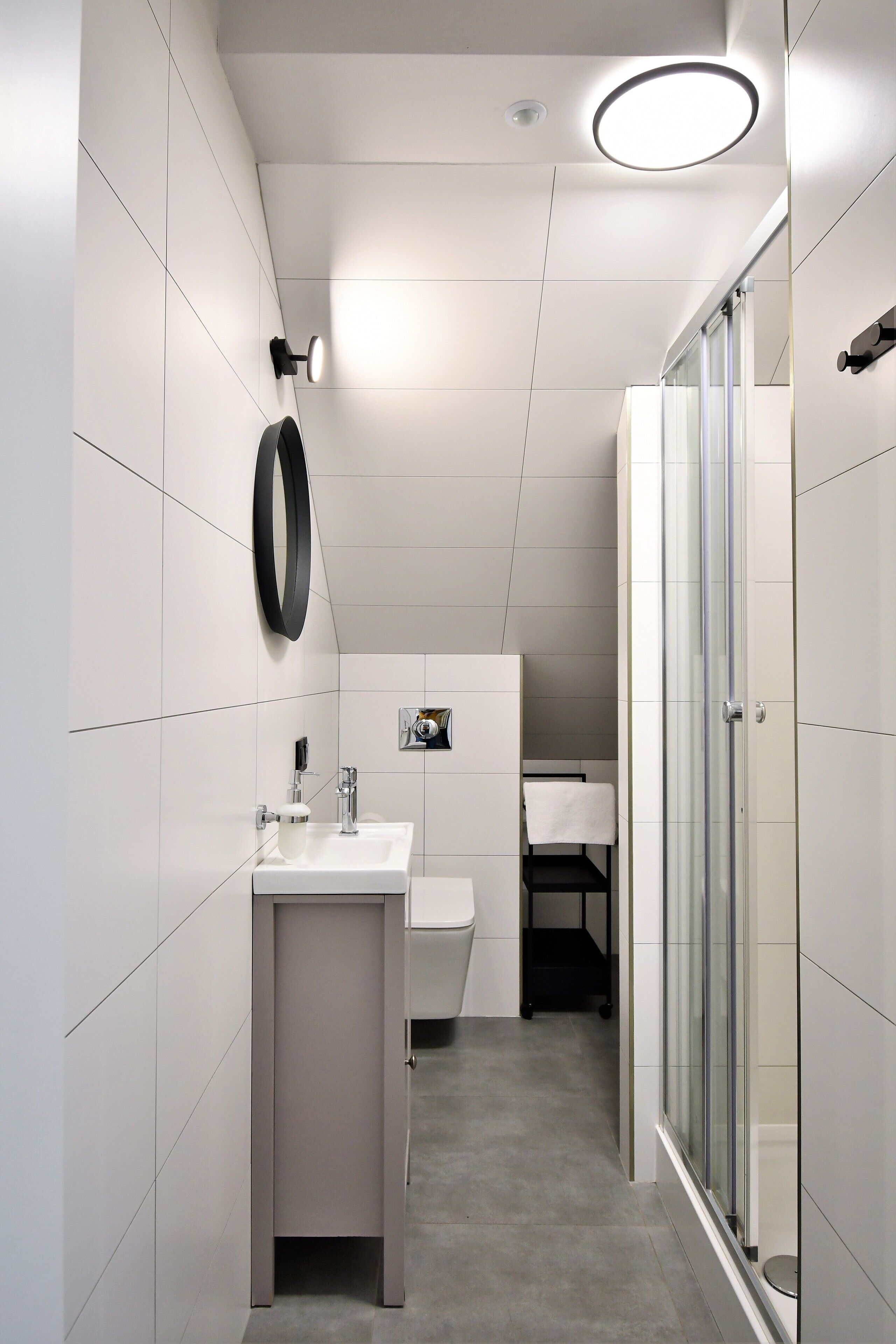 A modern bathroom with a white sink, mirror, and glass shower enclosure.