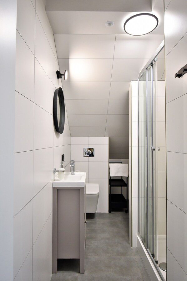 A modern bathroom with a white sink, mirror, and glass shower enclosure.