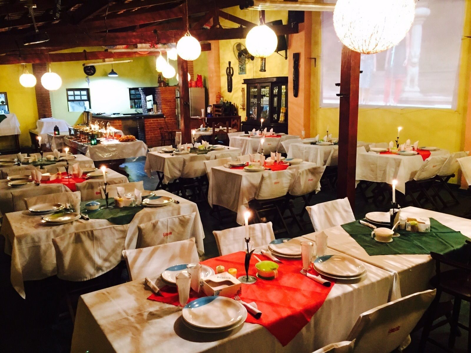 A restaurant with multiple round tables set for dining, each with white tablecloths and candles.