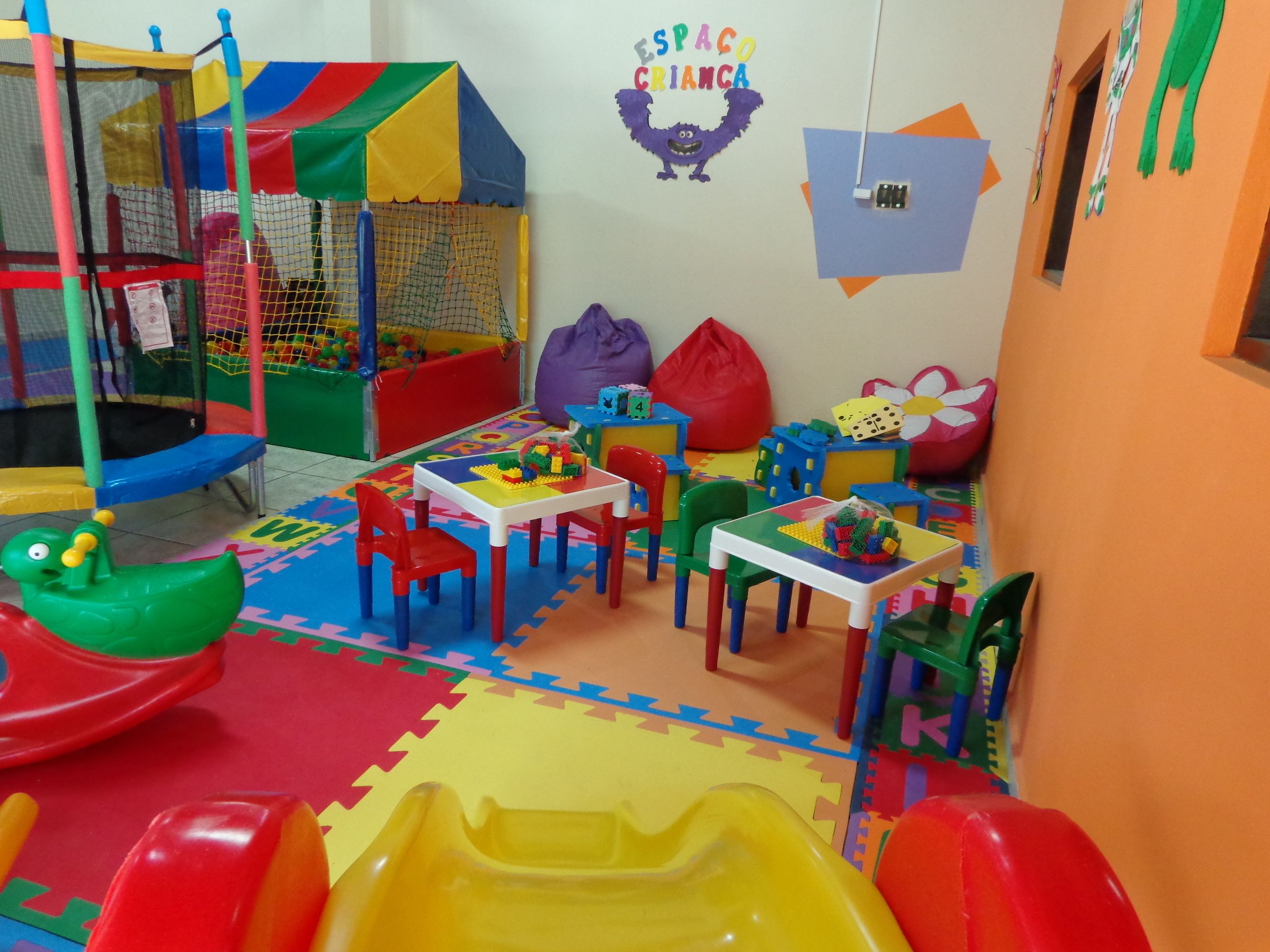 A children's play area with a trampoline, playpen, and colorful play structures.