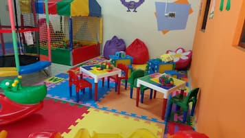 A children's play area with a trampoline, playpen, and colorful play structures.