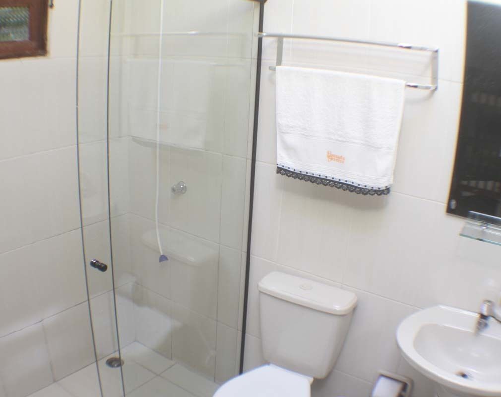 Un baño con cabina de ducha de vidrio, inodoro y lavamanos.
