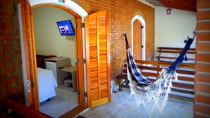 A room with a hammock, wooden doors, a TV, and a staircase. - Pousada Bezerra (Nazare Paulista)