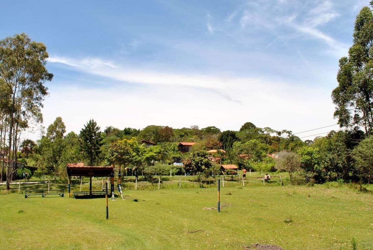 A grassy field with a wooden structure and a bench.