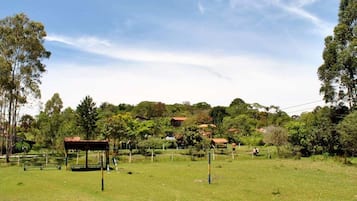 A grassy field with a wooden structure and a bench.
