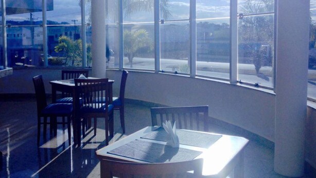 A dining area with large windows, a table, and chairs. - Habitat Hotel Pirassununga (Pirassununga)